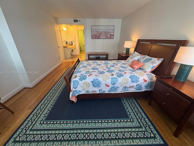 bedroom featuring connected bathroom and hardwood / wood-style flooring