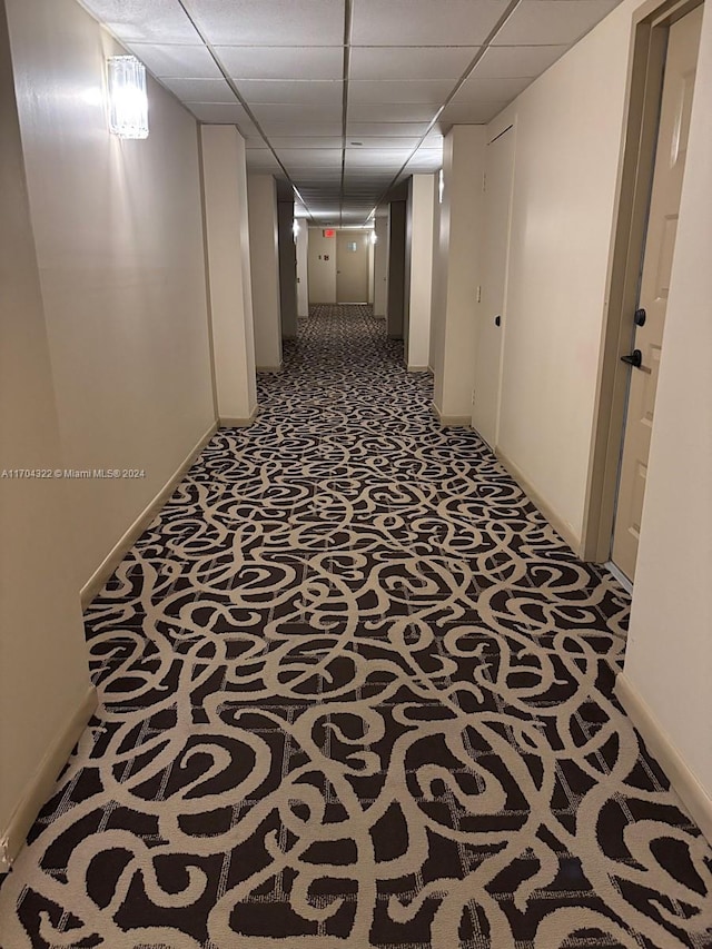 corridor featuring carpet floors and a paneled ceiling