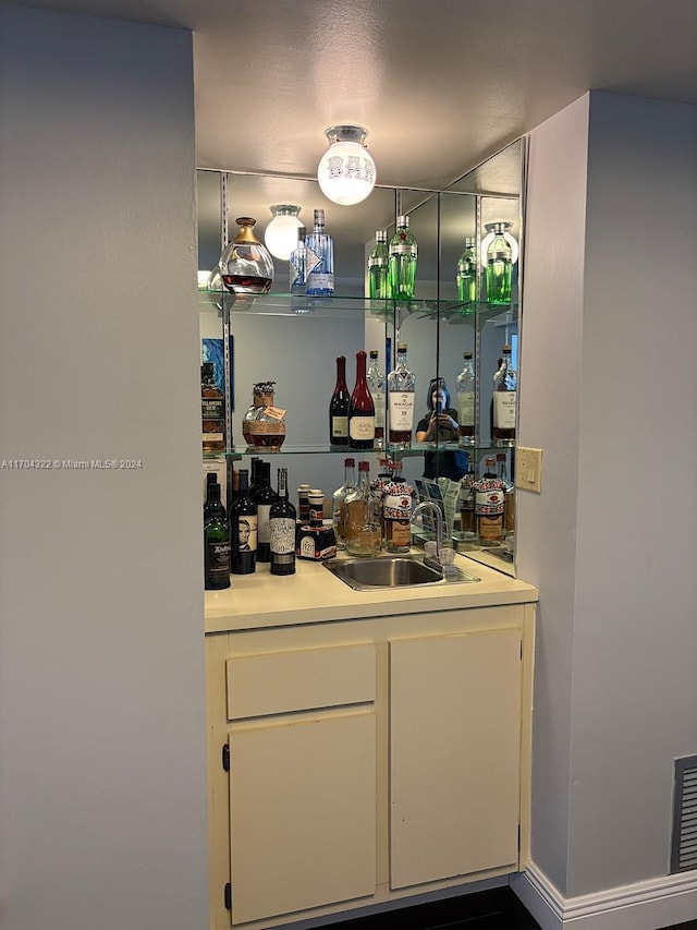 bar featuring white cabinets and sink