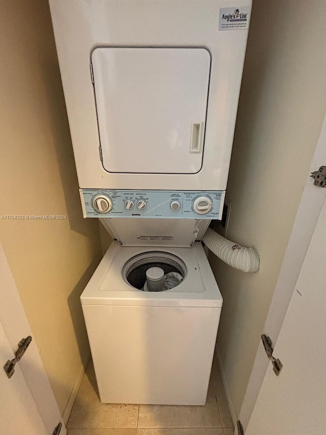 laundry room featuring light tile patterned floors and stacked washer and dryer