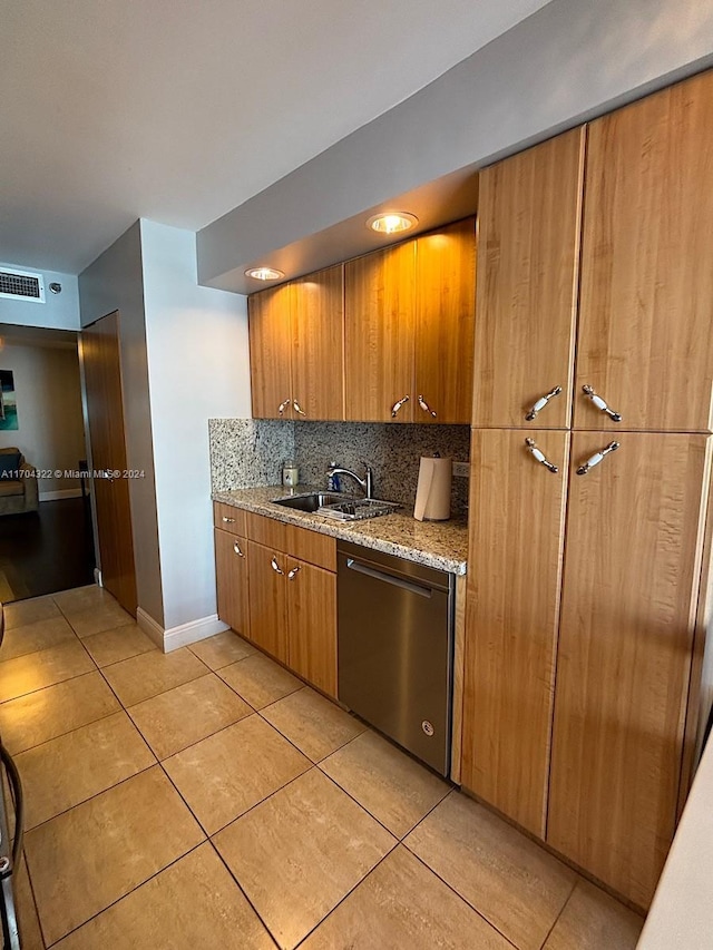 kitchen featuring decorative backsplash, light stone counters, sink, light tile patterned floors, and dishwasher