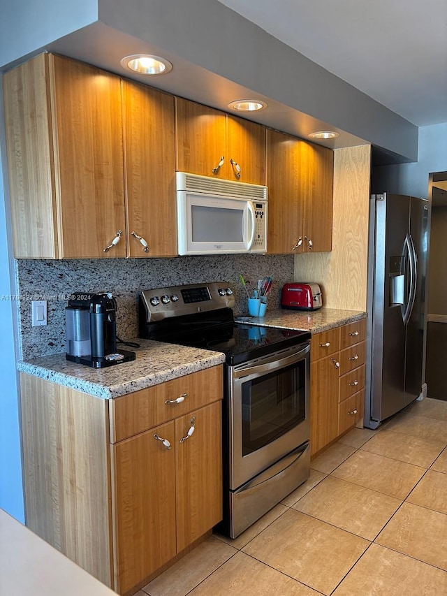 kitchen featuring decorative backsplash, light stone countertops, light tile patterned floors, and stainless steel appliances