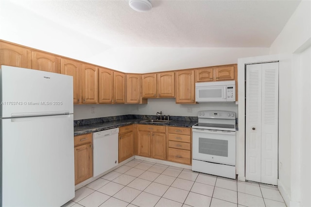 kitchen featuring vaulted ceiling, sink, light tile patterned floors, white appliances, and a textured ceiling