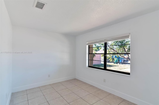 tiled spare room featuring a textured ceiling