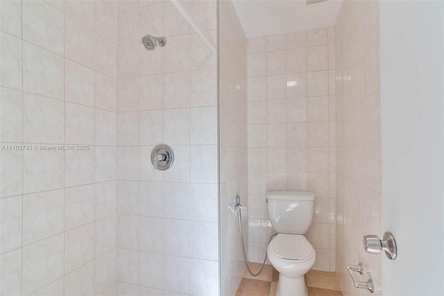 bathroom with tile patterned flooring, tiled shower, and toilet