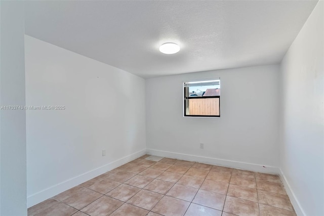 empty room featuring light tile patterned floors and a textured ceiling