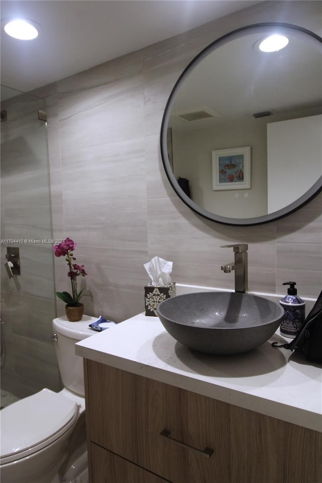 bathroom with tasteful backsplash, vanity, a shower, tile walls, and toilet