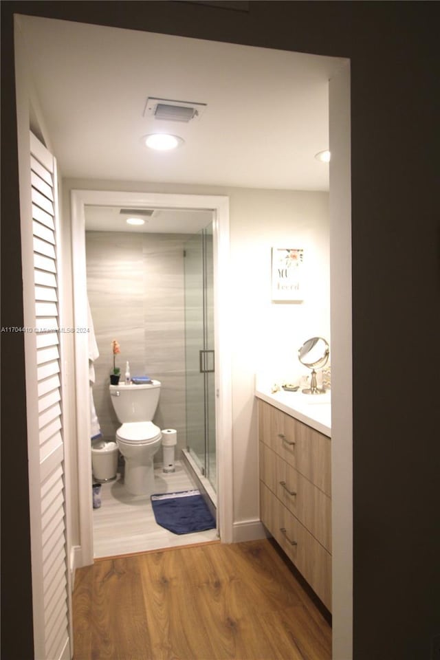 bathroom featuring wood-type flooring, vanity, toilet, and walk in shower