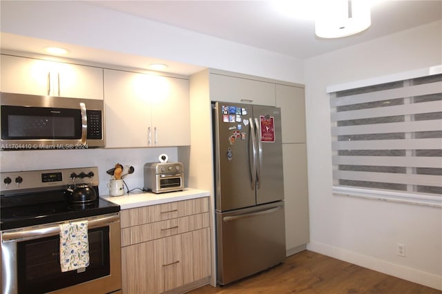 kitchen with appliances with stainless steel finishes, light brown cabinetry, and wood-type flooring