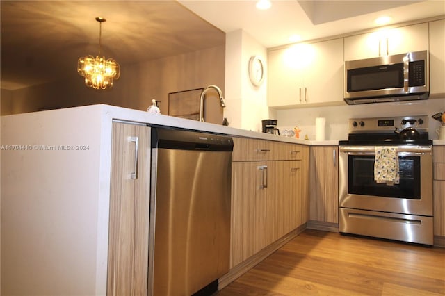 kitchen featuring light brown cabinets, stainless steel appliances, an inviting chandelier, light hardwood / wood-style flooring, and decorative light fixtures