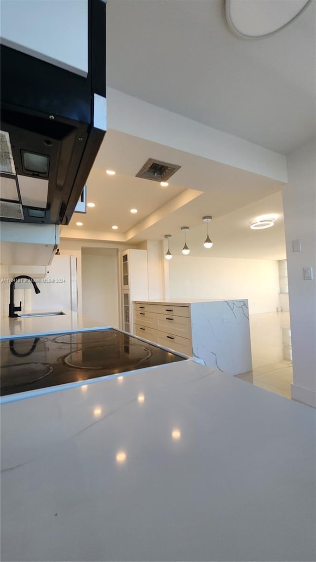 kitchen with a raised ceiling, white cabinetry, and sink