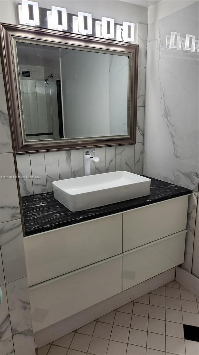 bathroom featuring a tile shower, vanity, and tile walls