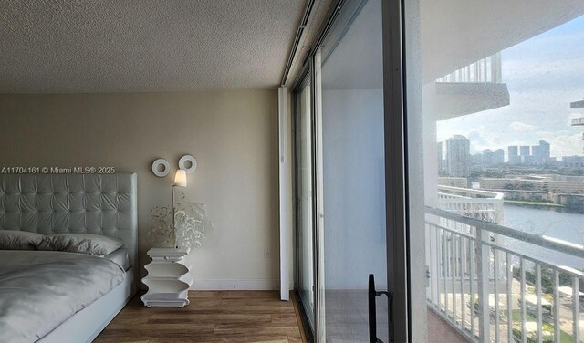 bedroom featuring a textured ceiling, hardwood / wood-style flooring, and multiple windows