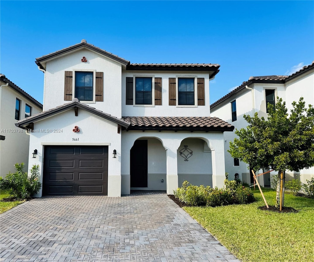 mediterranean / spanish-style home featuring a front yard and a garage