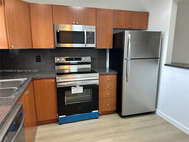 kitchen with decorative backsplash, appliances with stainless steel finishes, light hardwood / wood-style flooring, and sink