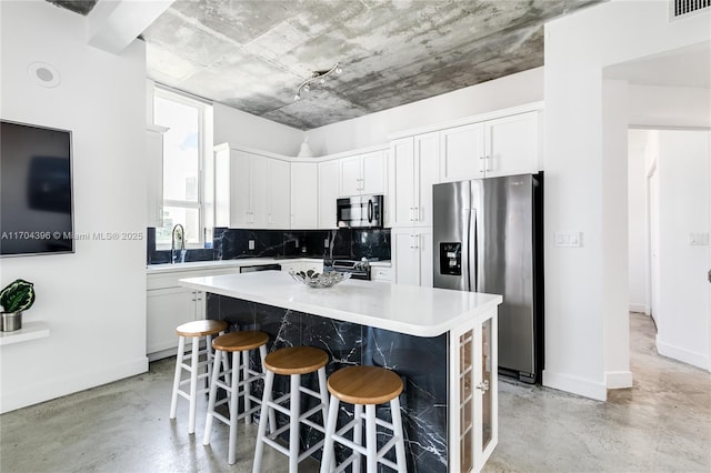 kitchen with tasteful backsplash, a center island, a kitchen bar, white cabinetry, and stainless steel fridge