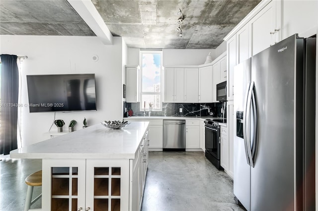 kitchen featuring backsplash, a center island, black appliances, a kitchen bar, and white cabinetry