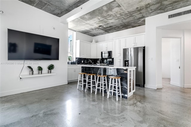 kitchen with white cabinetry, a kitchen bar, stainless steel refrigerator with ice dispenser, backsplash, and a kitchen island