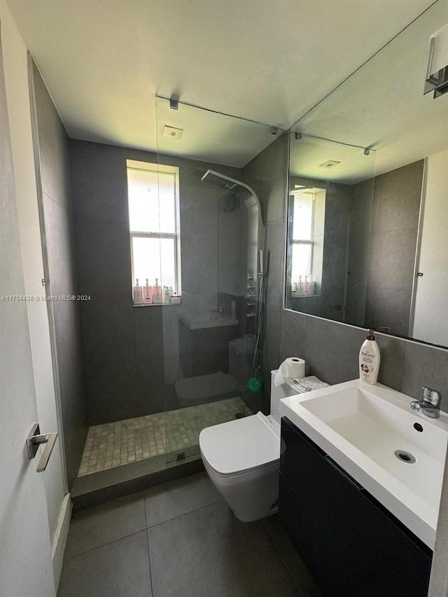 bathroom with vanity, tile patterned floors, toilet, tile walls, and a tile shower