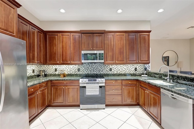 kitchen with appliances with stainless steel finishes, tasteful backsplash, sink, dark stone countertops, and light tile patterned flooring