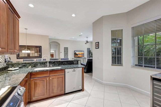 kitchen featuring pendant lighting, sink, dark stone countertops, light tile patterned flooring, and stainless steel appliances