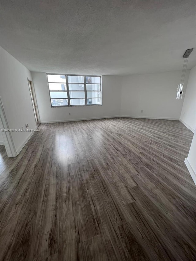 unfurnished room featuring a textured ceiling and dark hardwood / wood-style flooring