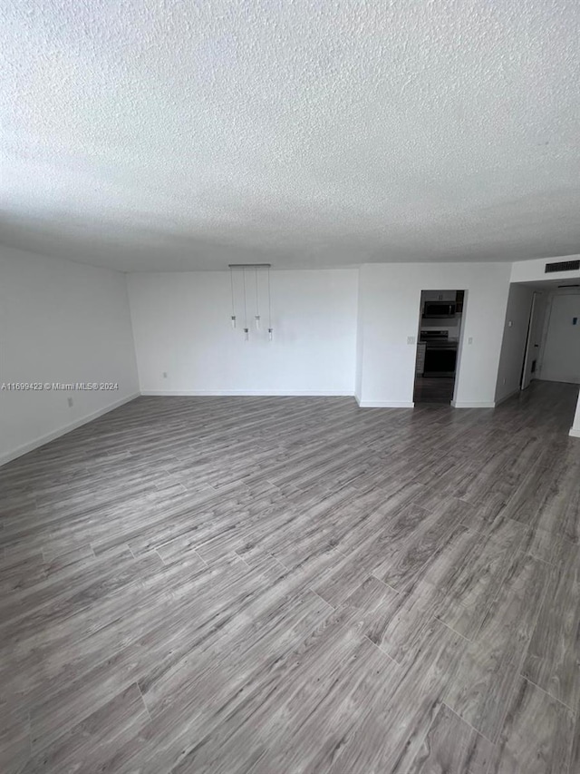 unfurnished living room with wood-type flooring and a textured ceiling