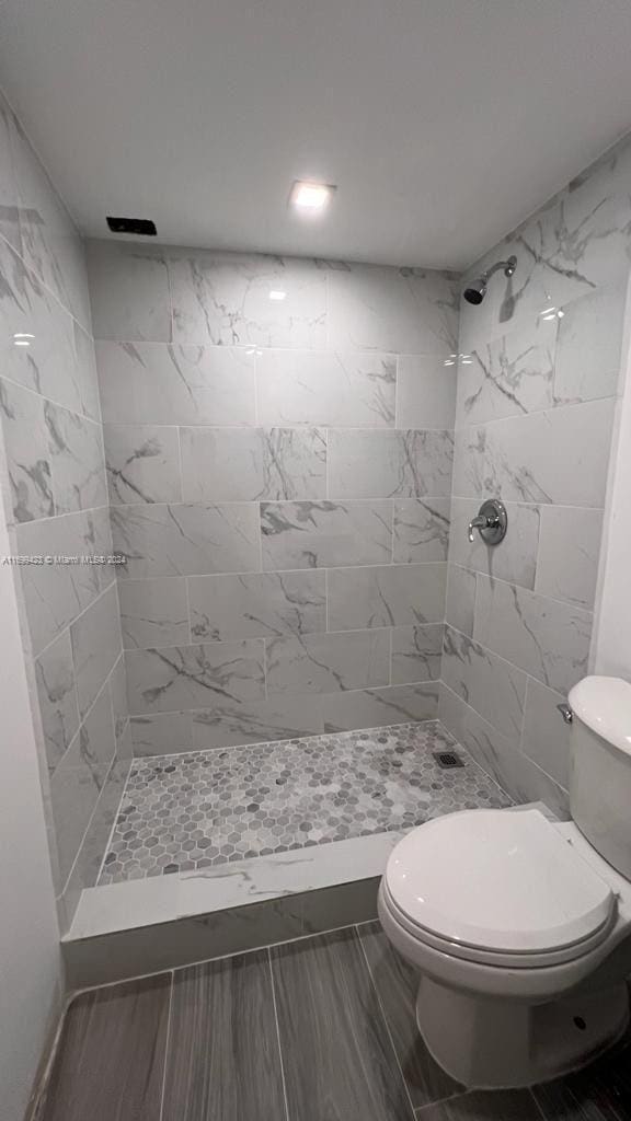 bathroom featuring toilet and a tile shower