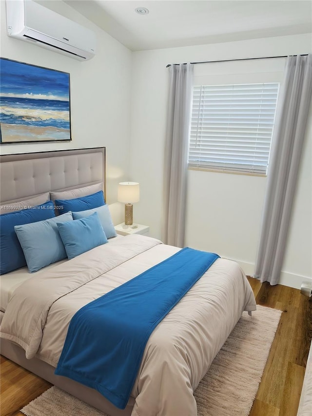 bedroom featuring hardwood / wood-style floors and an AC wall unit