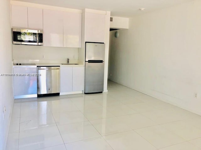 kitchen with light tile patterned flooring, stainless steel appliances, white cabinetry, and sink