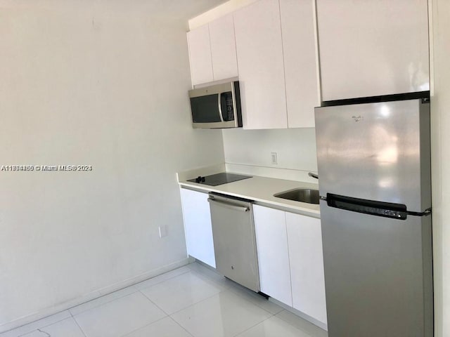 kitchen featuring light tile patterned floors, stainless steel appliances, white cabinetry, and sink