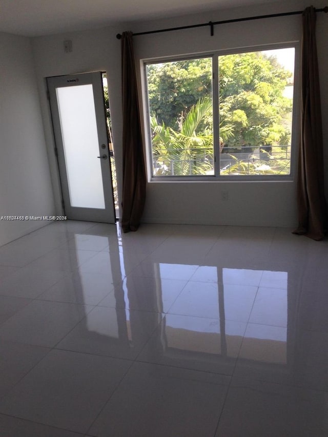 tiled spare room featuring plenty of natural light