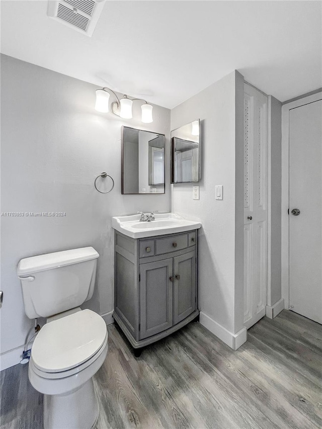 bathroom with wood-type flooring, vanity, and toilet