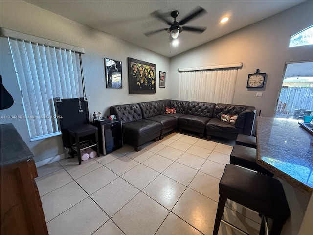 living room featuring ceiling fan, light tile patterned floors, and lofted ceiling