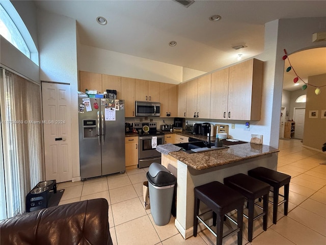 kitchen with sink, light tile patterned floors, light brown cabinetry, appliances with stainless steel finishes, and kitchen peninsula