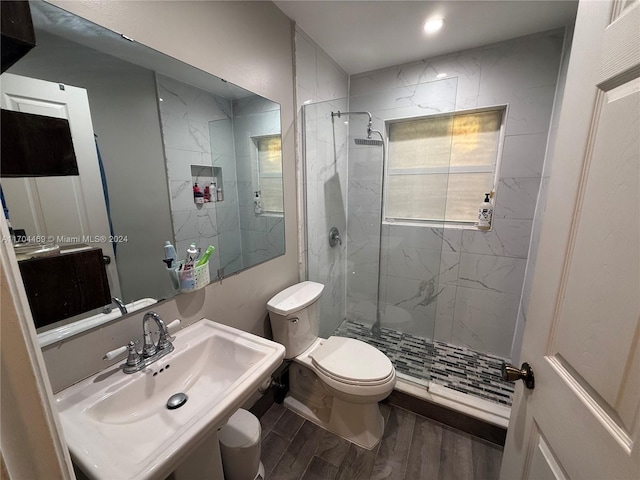 bathroom featuring tiled shower, toilet, wood-type flooring, and sink