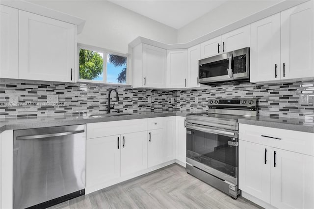 kitchen featuring light parquet floors, sink, decorative backsplash, white cabinetry, and stainless steel appliances