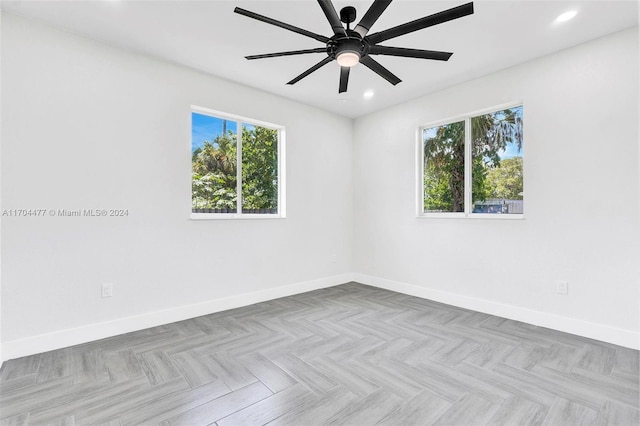 empty room featuring a wealth of natural light, light parquet floors, and ceiling fan