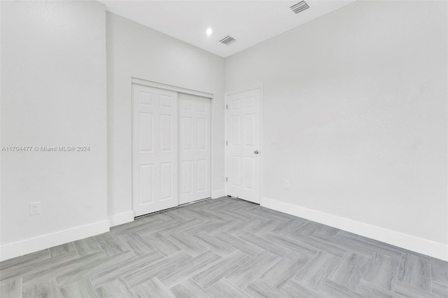 unfurnished bedroom with light parquet floors and a closet