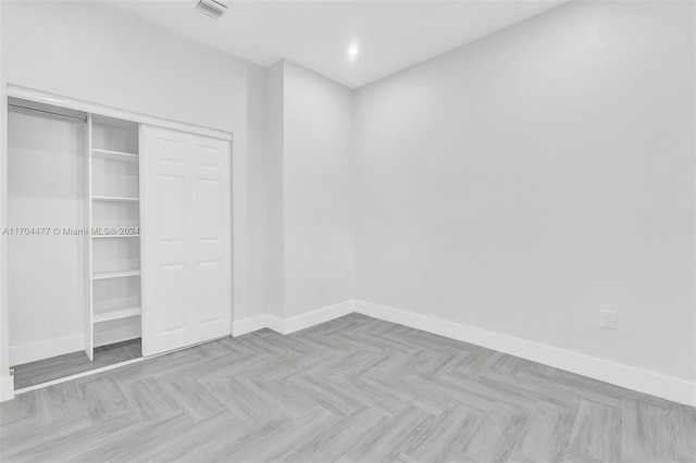 unfurnished bedroom featuring light parquet flooring and a closet