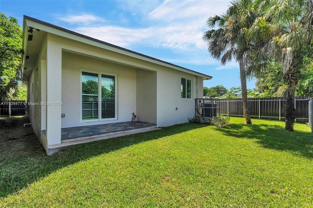 rear view of property featuring a lawn and central air condition unit