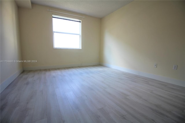 unfurnished room featuring a textured ceiling and light hardwood / wood-style flooring