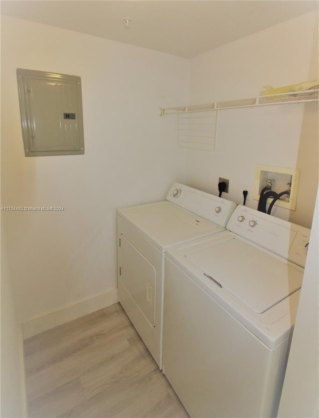 laundry room featuring electric panel, light hardwood / wood-style flooring, and washing machine and dryer