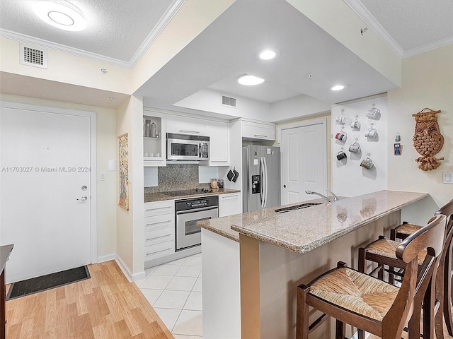 kitchen featuring kitchen peninsula, sink, white cabinets, and appliances with stainless steel finishes