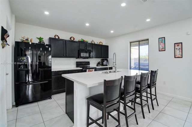 kitchen featuring decorative backsplash, a kitchen breakfast bar, sink, black appliances, and a center island with sink