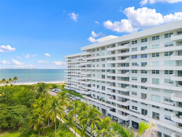 view of building exterior featuring a water view and a beach view