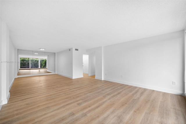 unfurnished living room featuring a textured ceiling and light hardwood / wood-style flooring