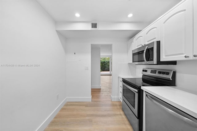 kitchen with white cabinets, light wood-type flooring, and appliances with stainless steel finishes