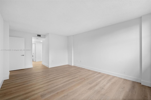 unfurnished room with a textured ceiling and light hardwood / wood-style floors