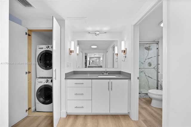 bathroom featuring walk in shower, stacked washing maching and dryer, and hardwood / wood-style flooring